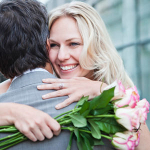 счастливая женщина с букетом роз обнимает мужчину