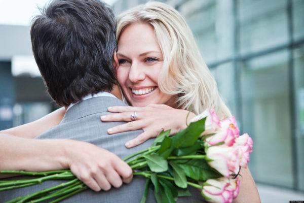 счастливая женщина с букетом роз обнимает мужчину